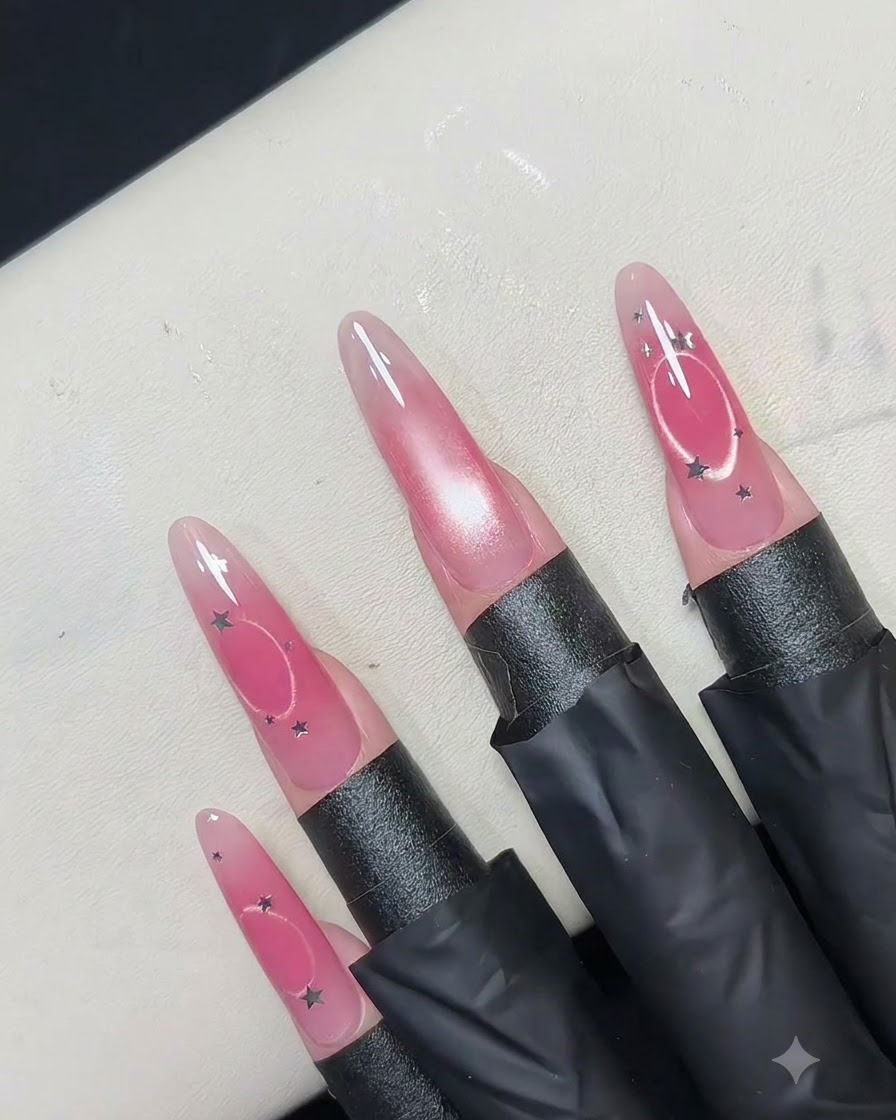 Uno strumento magnetico circolare cavo tenuto sopra ununghia rosa per spingere i riflessi magnetici verso lesterno formando un anello.