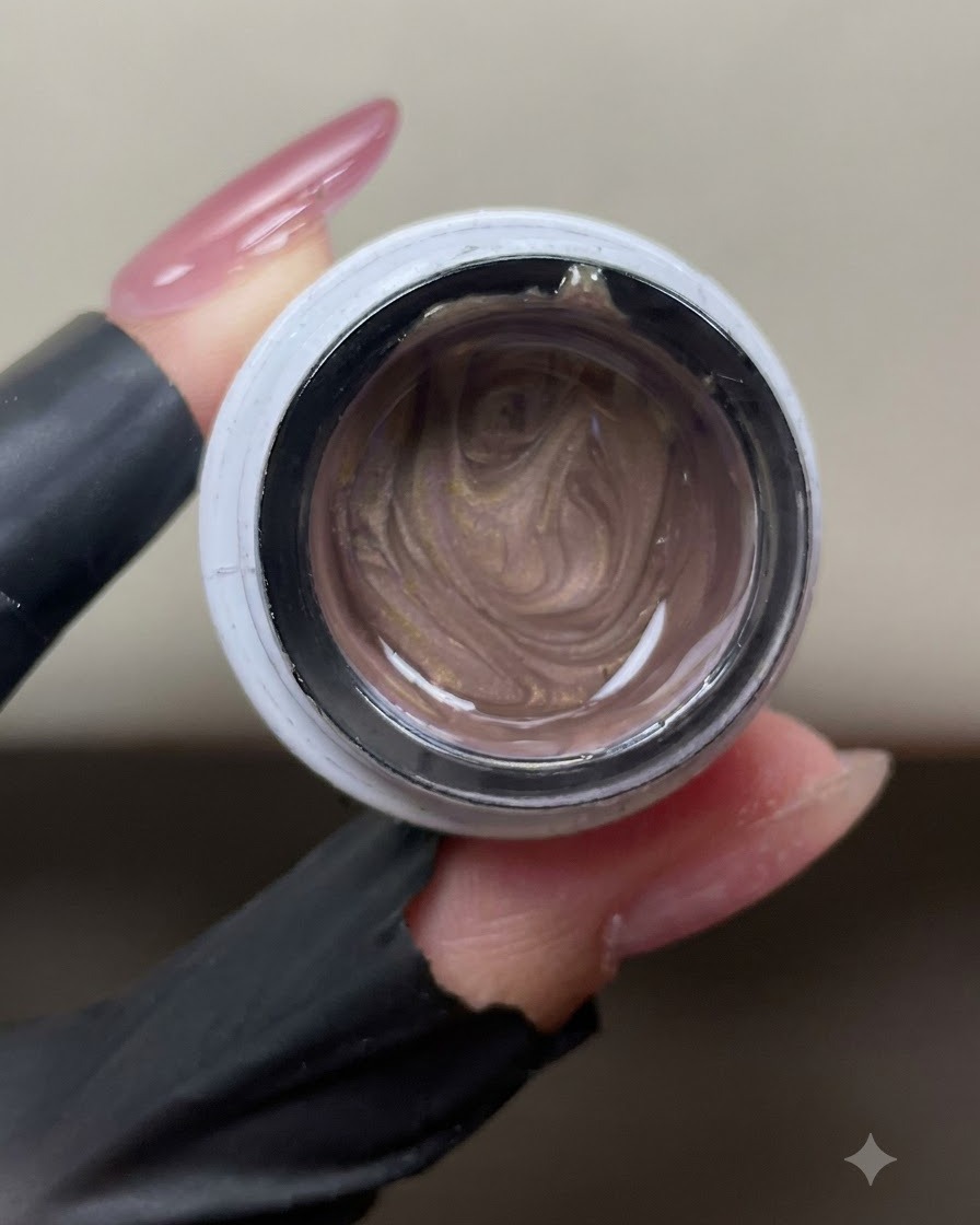 Un vasetto aperto di gel cat-eye rosa-oro che mostra le particelle metalliche magnetiche allinterno.