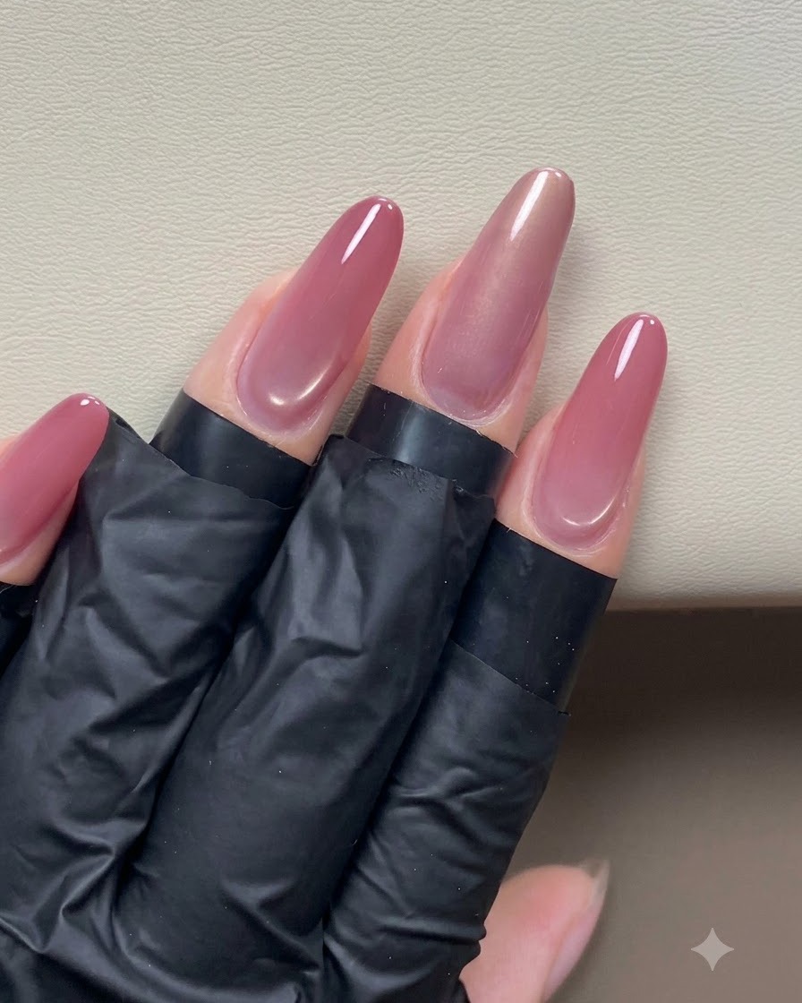 Una mano che tiene un magnete a penna vicino a ununghia cat-eye per modellare un effetto di luce laterale.