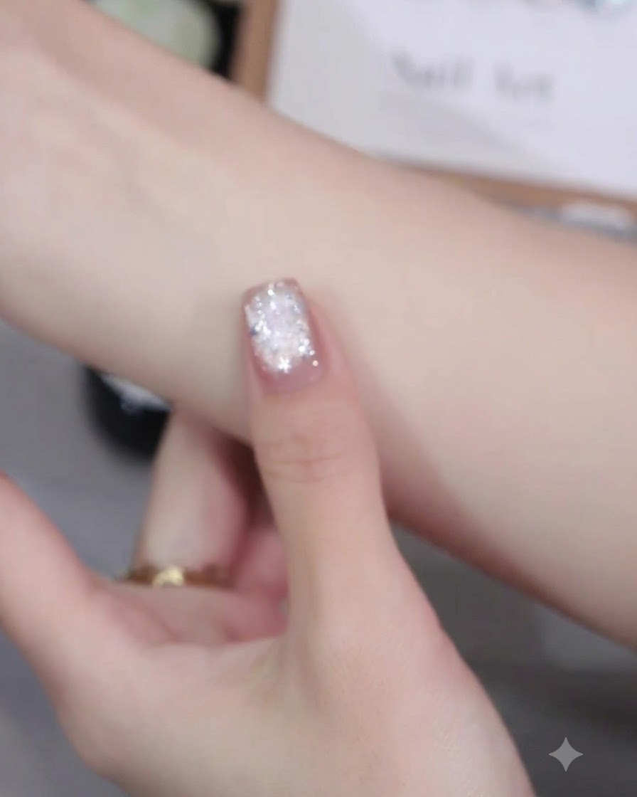 Un pennello per unghie che applica in modo uniforme lo smalto gel cat-eye rosa sulla superficie di ununghia.