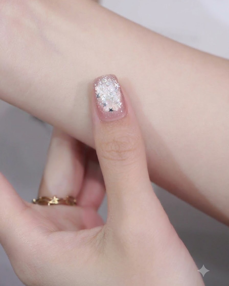 Un primo piano di ununghia curata con un pezzo di glitter a stella posizionato sulla punta sopra un dettaglio di nail art con cornice.