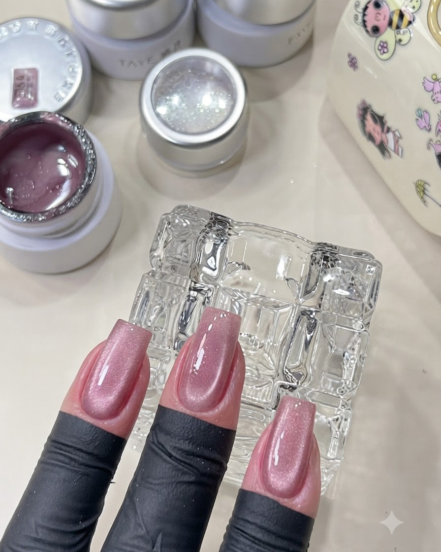Una mano che mostra unghie rosa cat-eye polimerizzate con una finitura brillante.