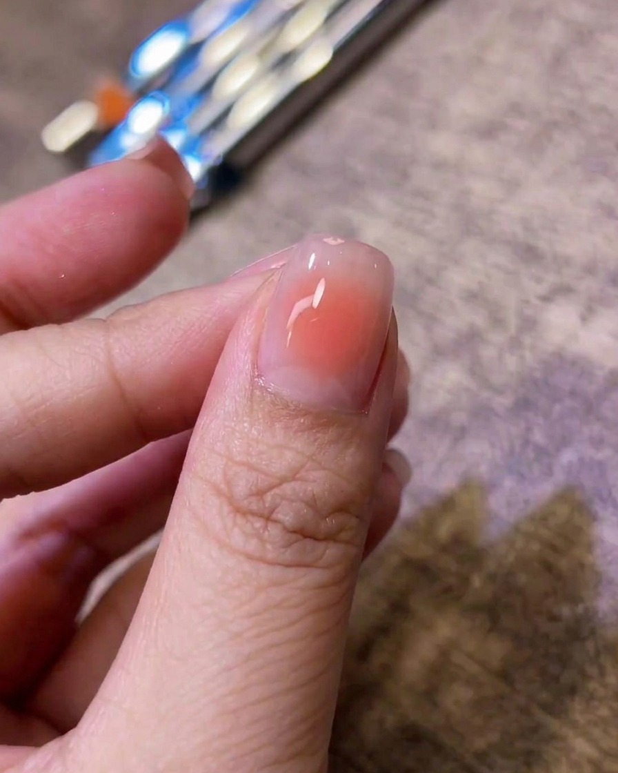 Primo piano di ununghia lucida con un centro rosa blush dolcemente sfumato su una base nude.