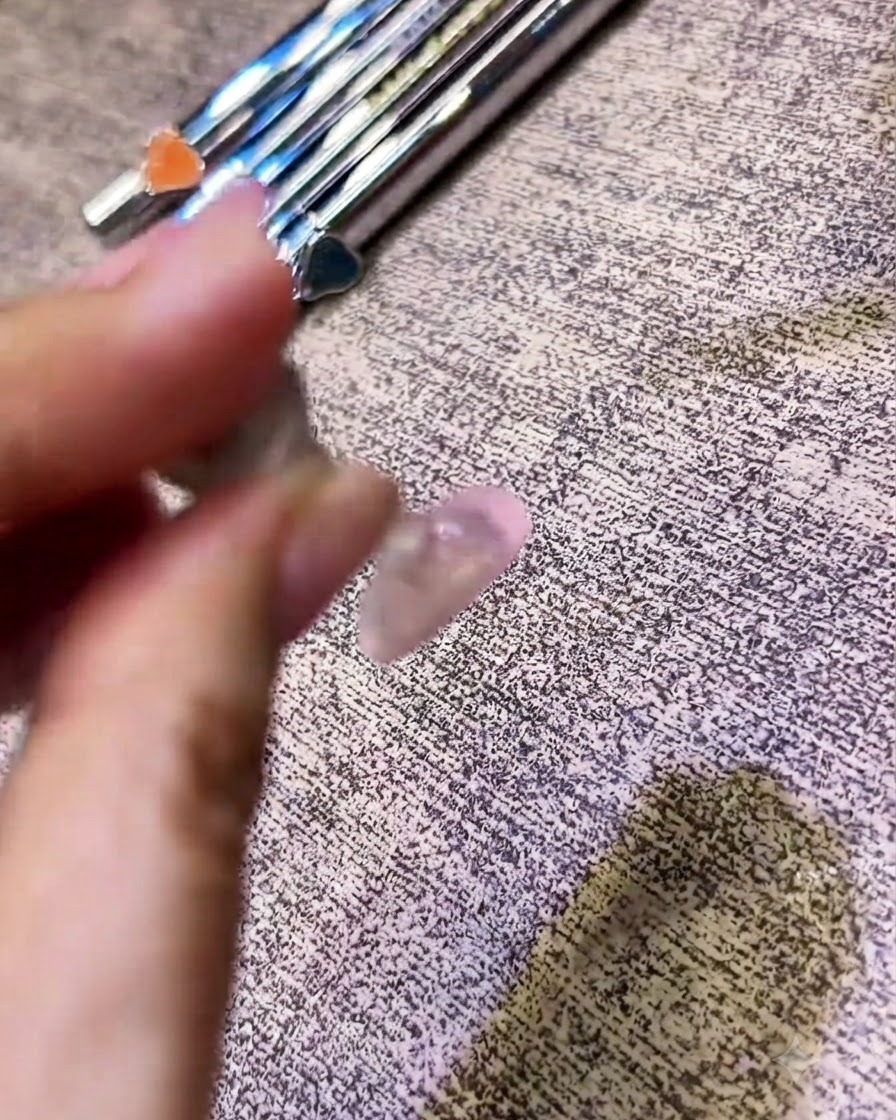 Un pennellino che applica un top coat trasparente su ununghia con finitura cromata.