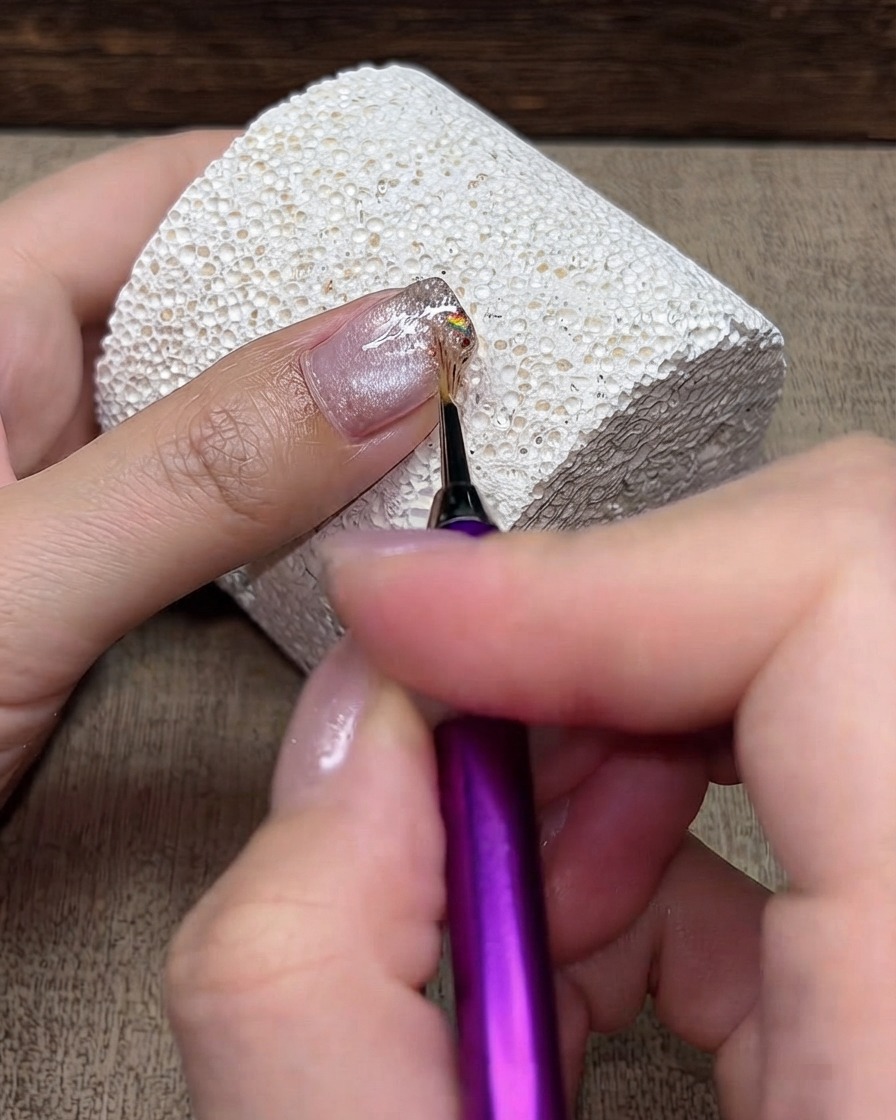 Un pennello da dettaglio fine che spinge leggermente allindietro le particelle di glitter dalla punta verso la cuticola.