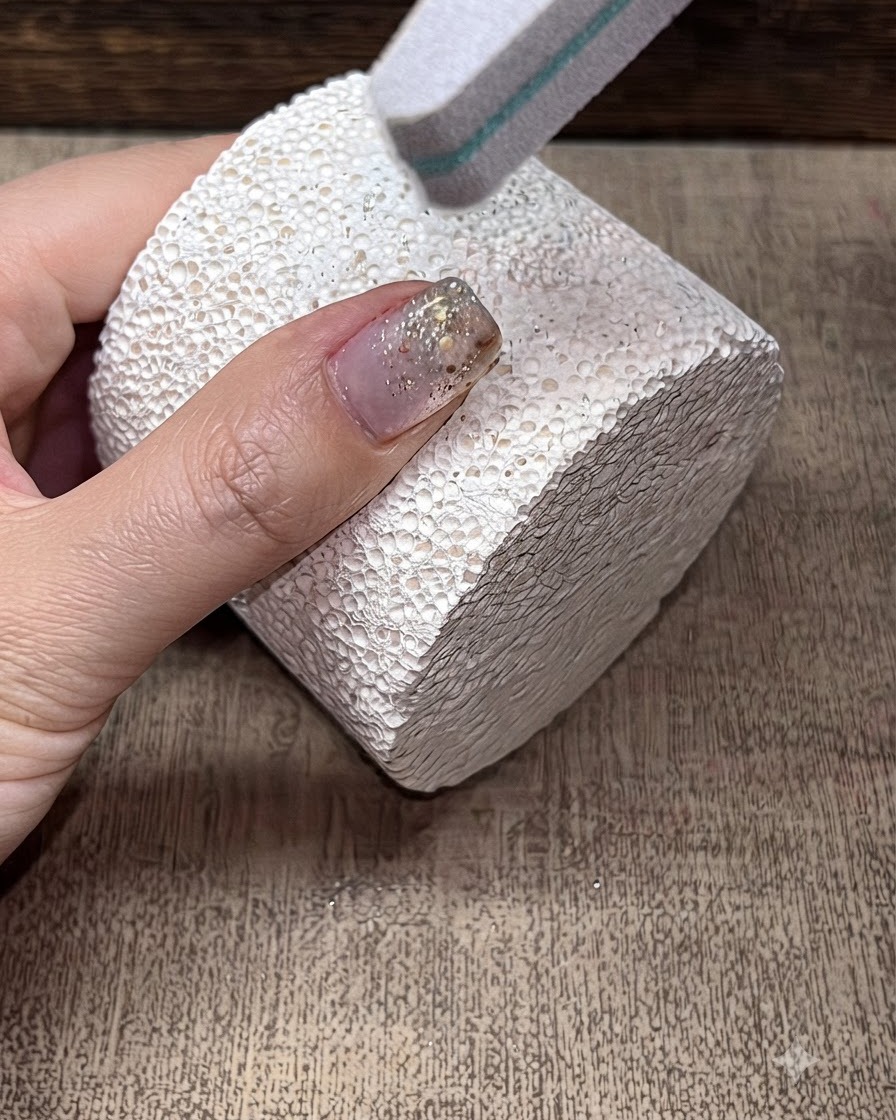 Una lima buffer a spugna che leviga la superficie di ununghia con manicure.