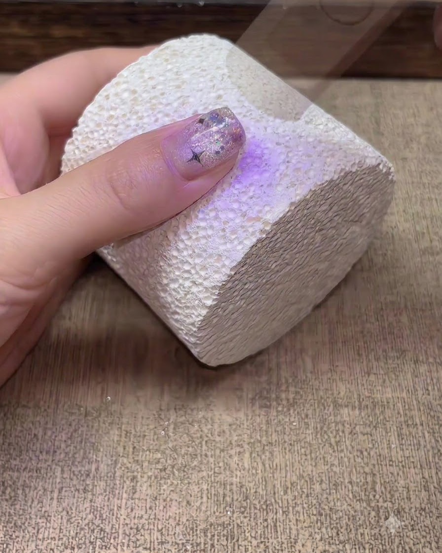 Una mano che polimerizza sotto una lampada per unghie UV LED viola.