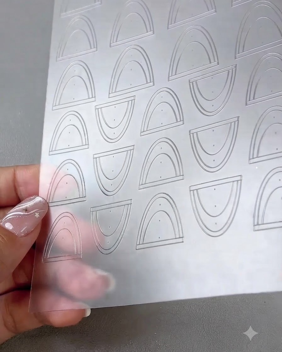 Una vista ravvicinata di un foglio trasparente contenente adesivi multipli curvi per French tip e nail art lineare.