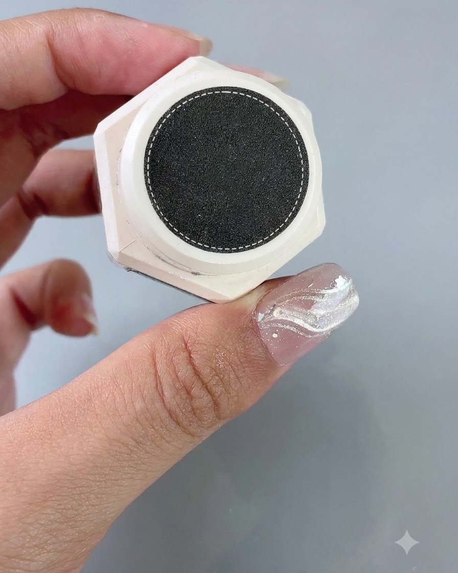Un contenitore di gel per styling e texture tenuto vicino a ununghia con una guida adesiva French applicata.