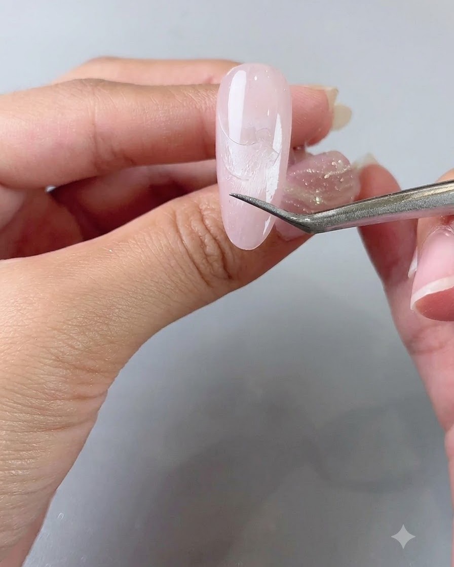 Delle pinzette rimuovono delicatamente un adesivo guida French, rivelando una linea pulita sullunghia.