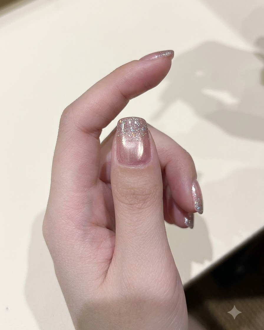 Un pennello per smalto che applica uno strato di gel glitter diamante scintillante su ununghia polimerizzata.