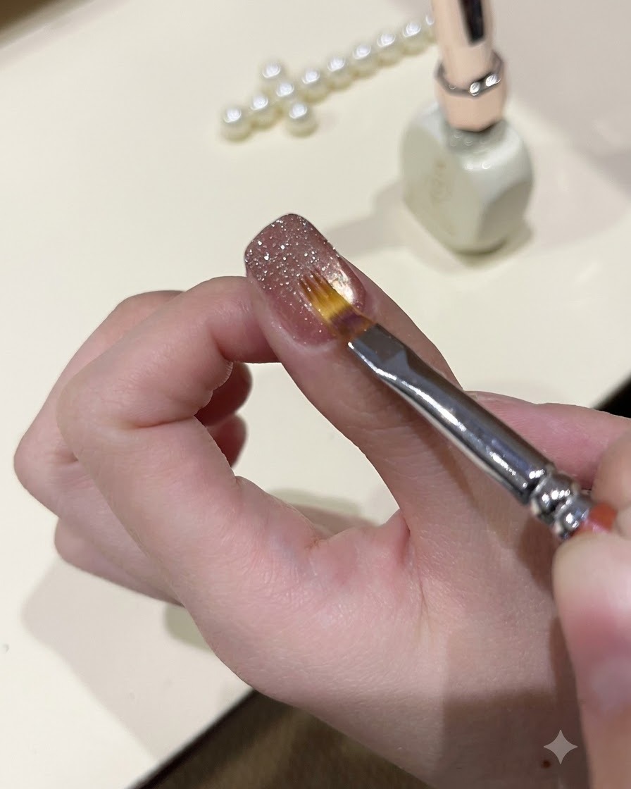 Un pennello da dettaglio fine che livella il gel glitter scintillante sulla superficie di ununghia manicurata.