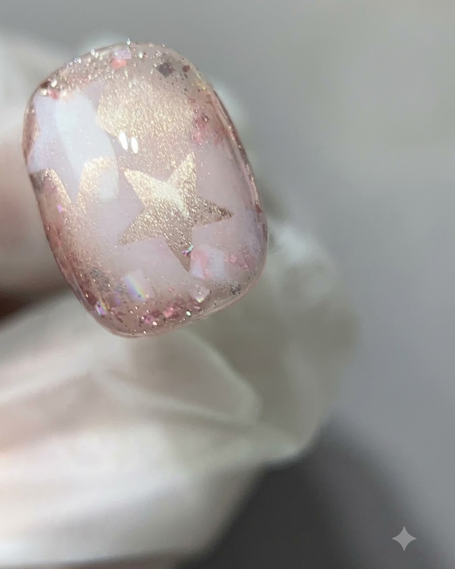 Una vista ravvicinata di ununghia in gel cat-eye rosa polimerizzata sotto una luce di polimerizzazione.