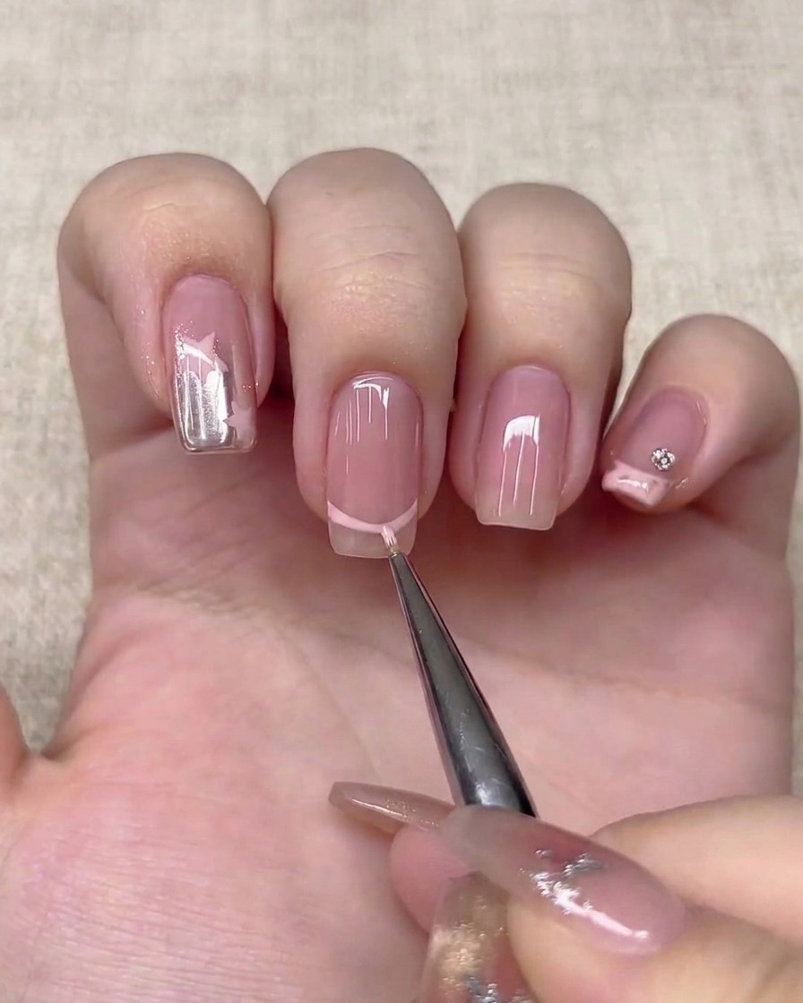 Un pennello liner sottile disegna una linea French rosa chiaro su ununghia.