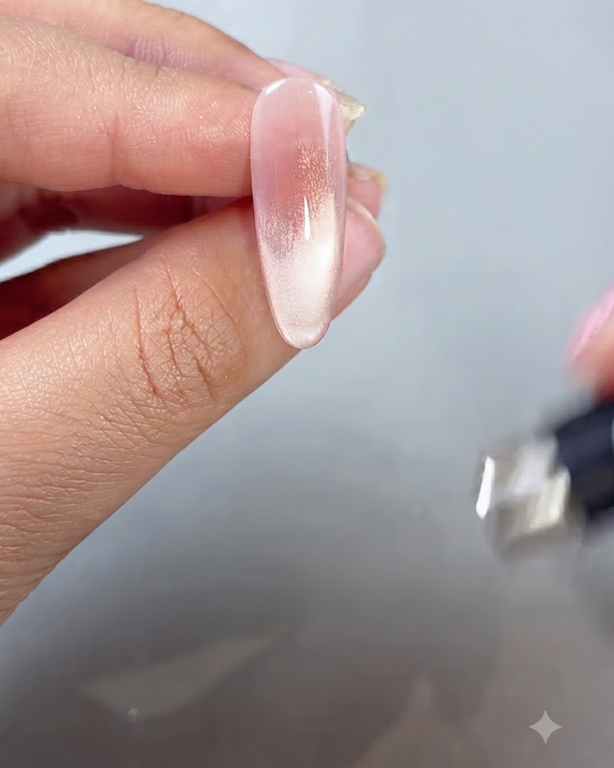 Una bacchetta magnetica tenuta vicino alla punta di un dito dipinta per modellare il riflesso cat-eye in uno stile French tip.
