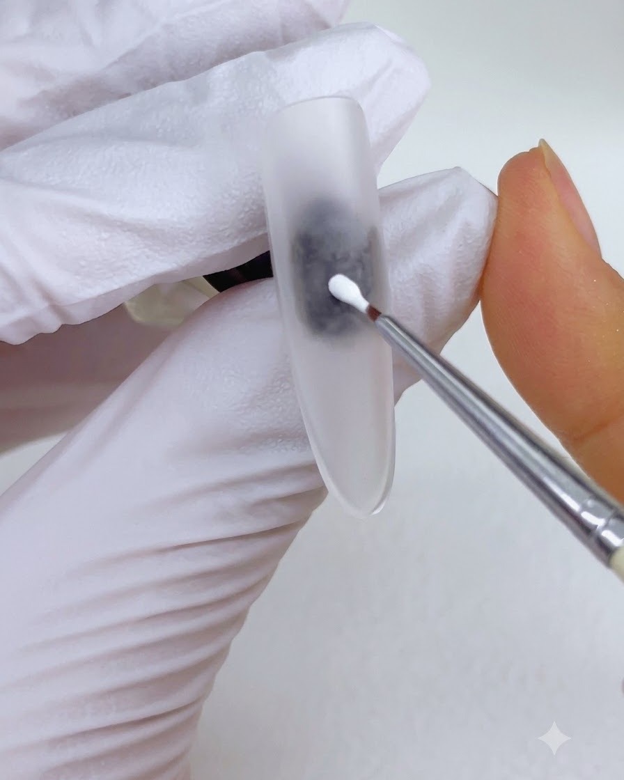 Un pennello a punta fine per dettagli che posiziona una goccia di gel da pittura bianco al centro della superficie di ununghia opaca.