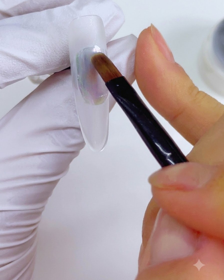 Un pennello per dettagli inumidito con detergente per unghie che viene delicatamente passato sullapplicazione di inchiostro multicolore sullunghia.