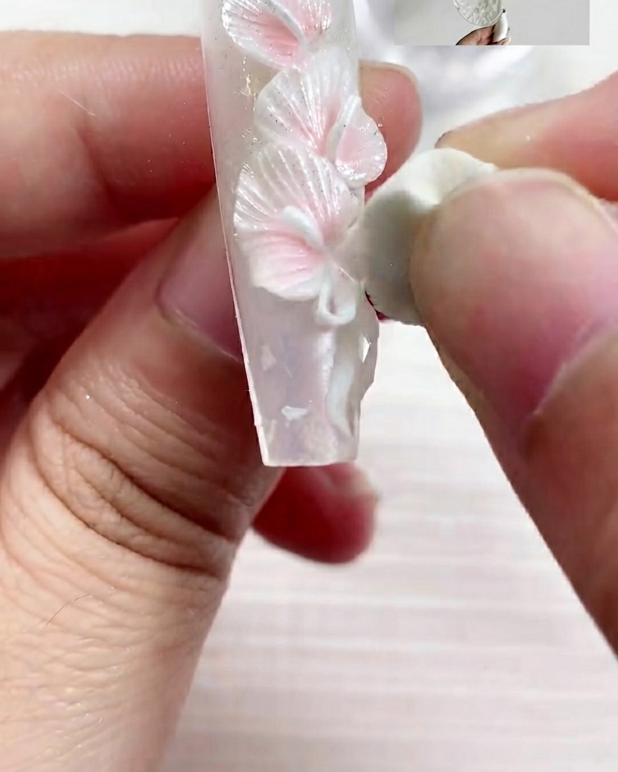 Un pennello piatto applica il gel con texture perla S03 sulla superficie dellunghia con passate fluide.