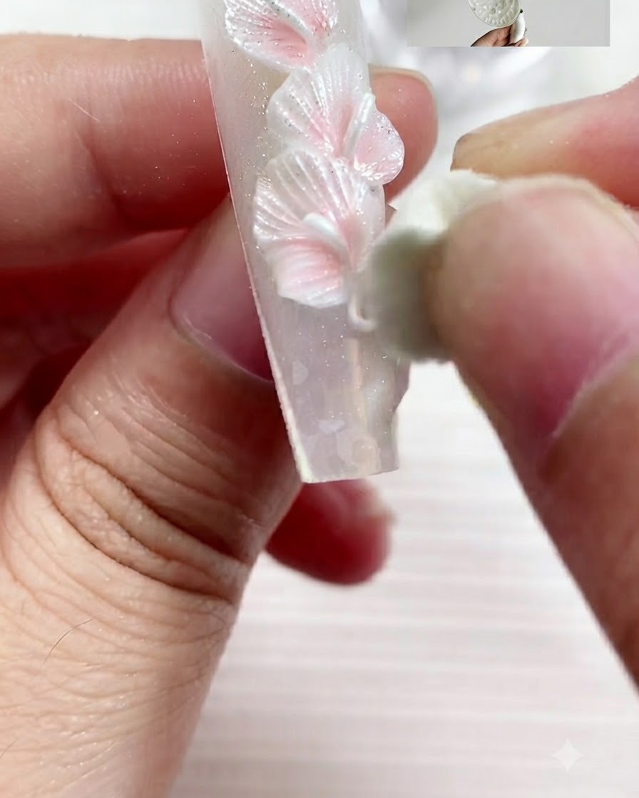 Uno strumento di scultura preme e modella un pezzo di gel in un petalo di calla appiattito.