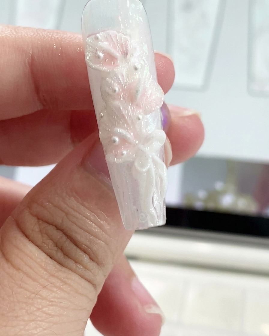 Uno strumento in silicone modella un fiocco in gel a nastro su ununghia decorata.