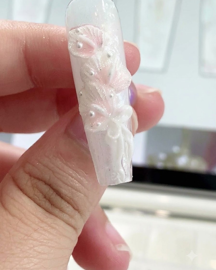 Una penna modellante in silicone liscia il nodo di un fiocco su un design di unghia scolpito.