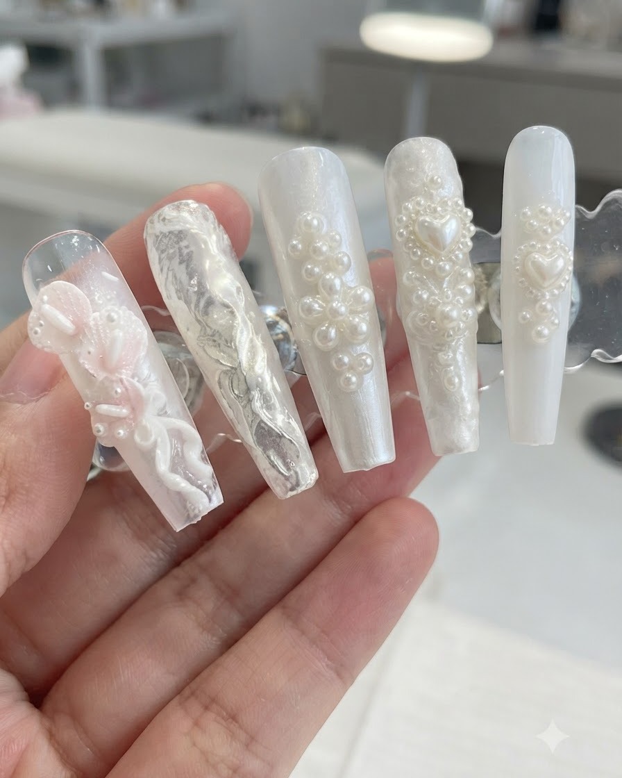 Un supporto da esposizione che mostra design di unghie 3D con perle e motivi floreali dopo aver rimosso la polvere di brillio in eccesso.