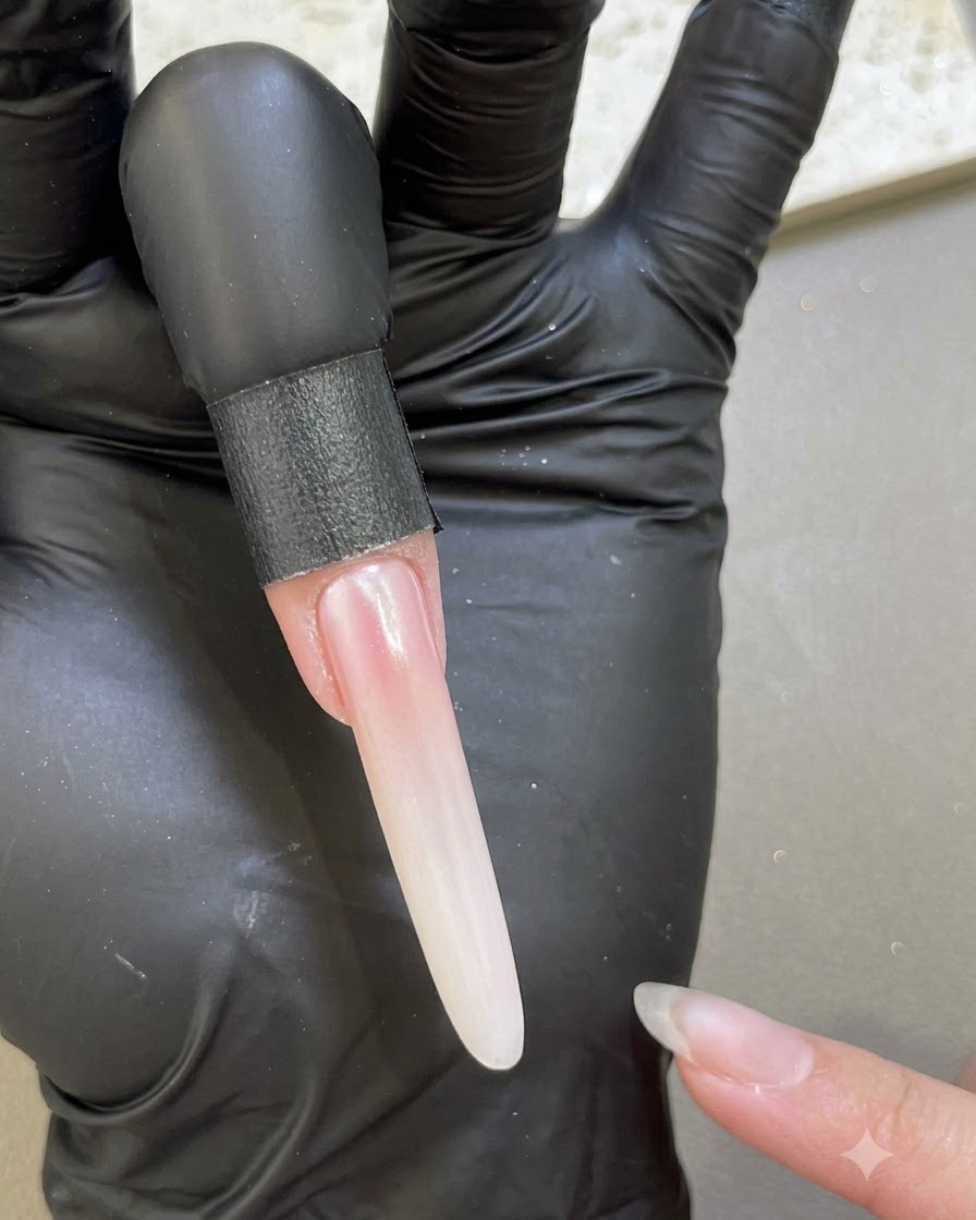 Ununghia allungata che mostra una finitura liscia e perlescente dopo la sigillatura con gel base lungo i bordi.