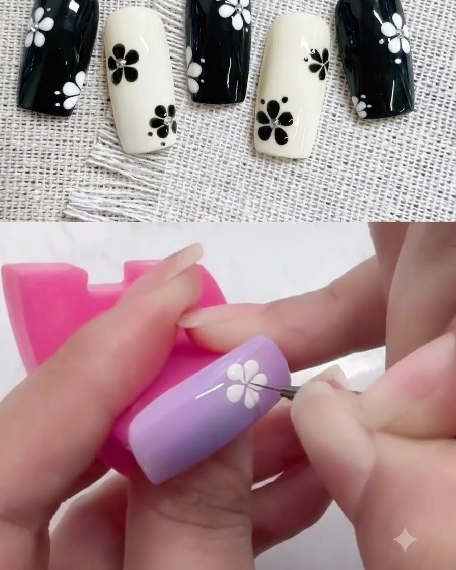 Un piccolo dotting tool posiziona un punto centrale nero in un design di fiore bianco su ununghia viola.