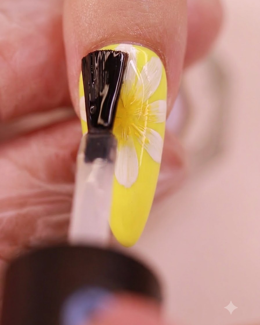 Un pennello applica uno strato trasparente di top coat no-wipe sopra il design di margherite dipinte.