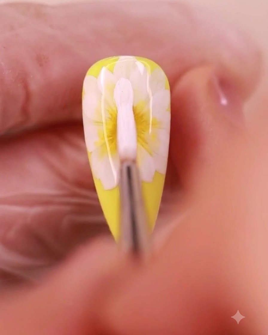 Un pennello per nail art applica gel bianco per formare un terzo strato di petali su un design a margherita.
