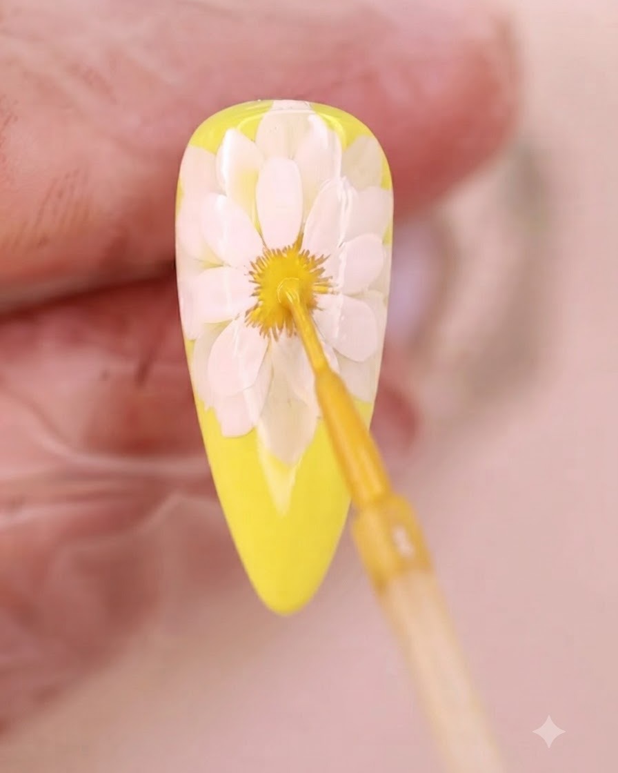 Un pennello sottile applica liquido giallo al centro sfumato del fiore.
