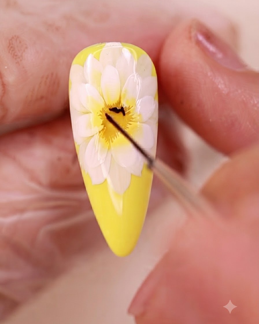 Un pennello liner sottile disegna linee nere sottili al centro della nail art floreale.