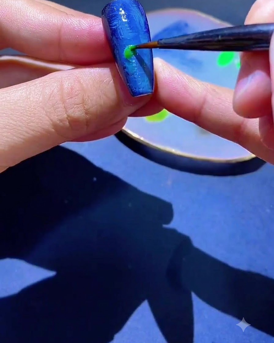 Un pennello a punta fine che applica una macchia di smalto gel verde su ununghia blu testurizzata.