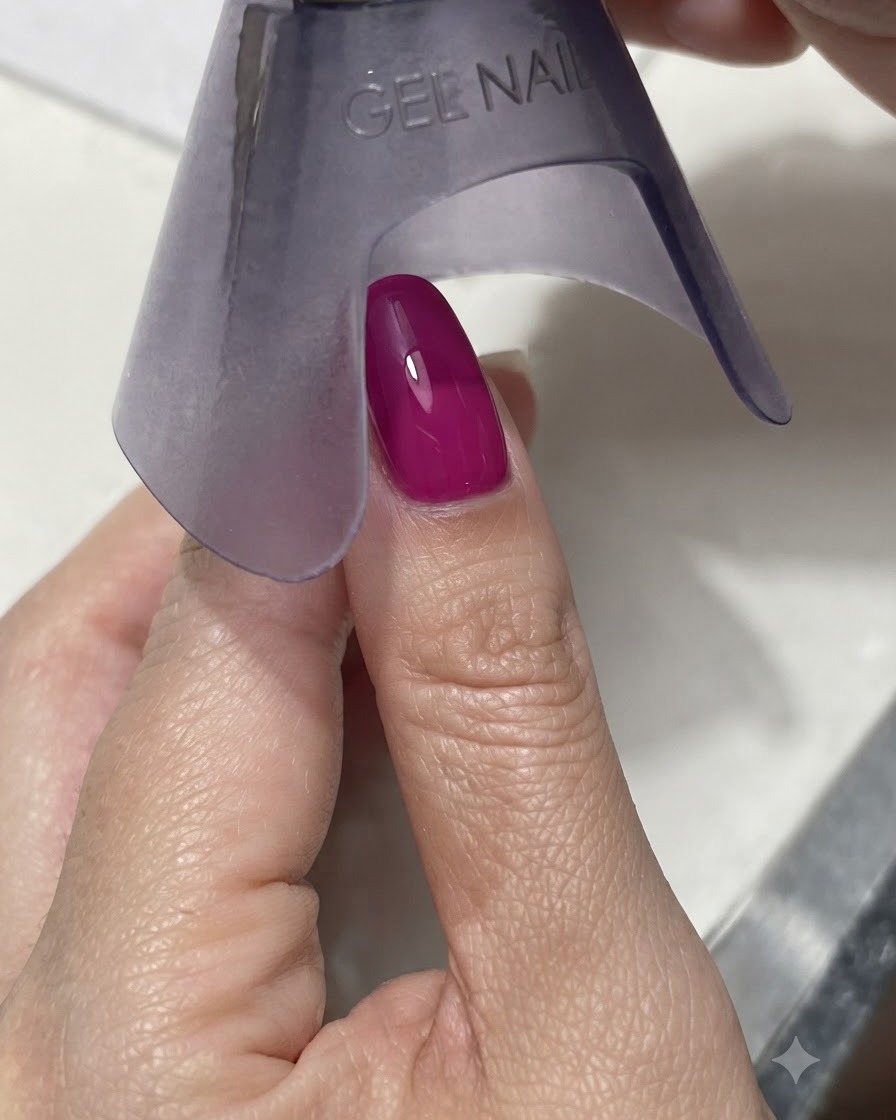 Una lampada UV/LED portatile viola che polimerizza ununghia vibrante magenta scuro o blu sotto una luce intensa.