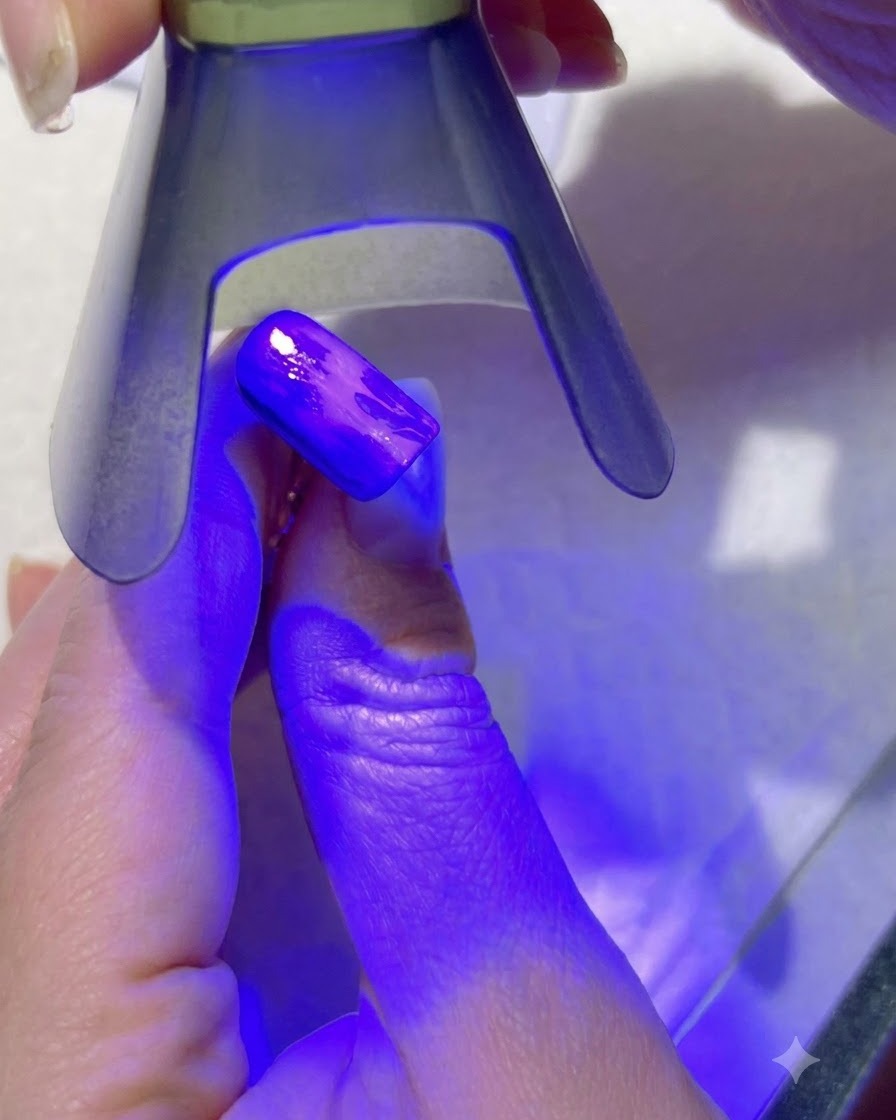 Una lampada UV viola che polimerizza i dettagli delle foglie verde chiaro su ununghia dipinta.