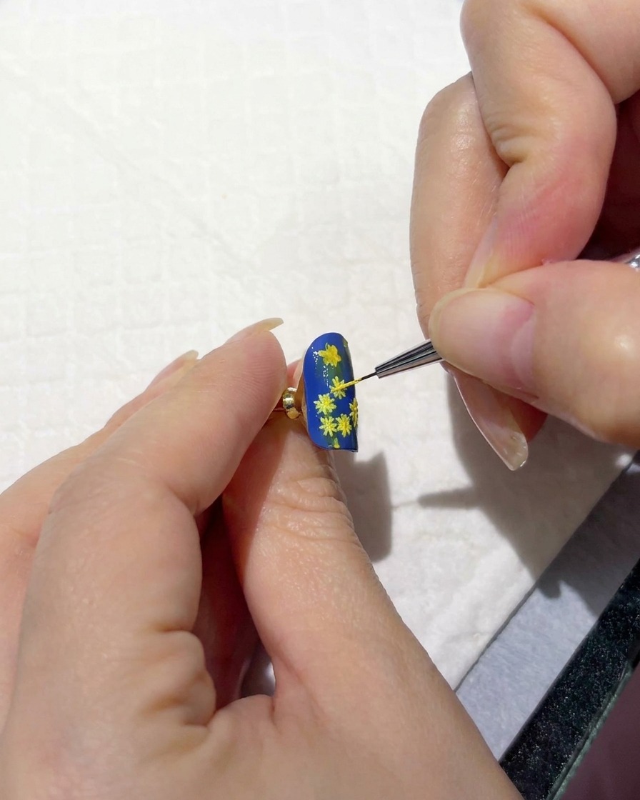 Una mano che tiene ununghia sotto una lampada di polimerizzazione portatile.