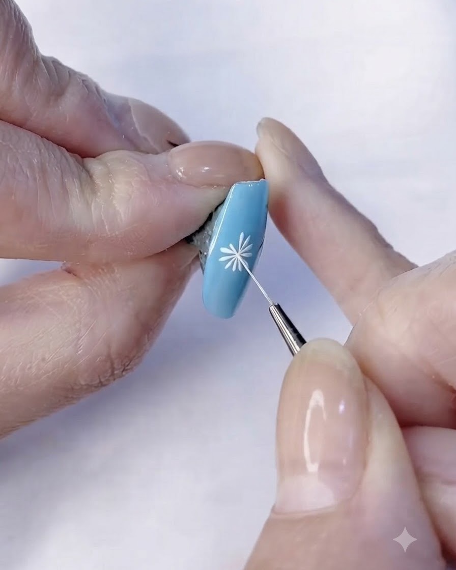 Un pennello fine rifinisce i dettagli dei petali bianchi di un design di nail art con margherite.
