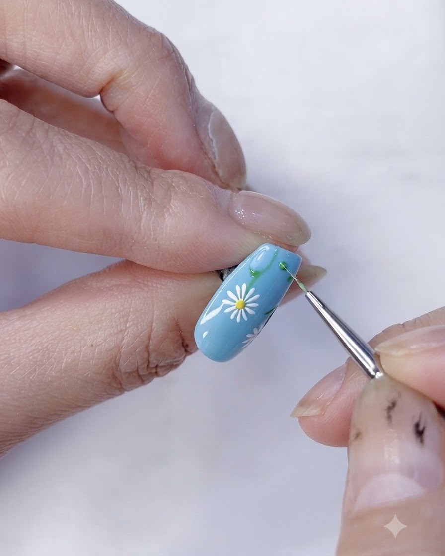 Vista in primo piano di un design di nail art con margherite completato su una base azzurra.