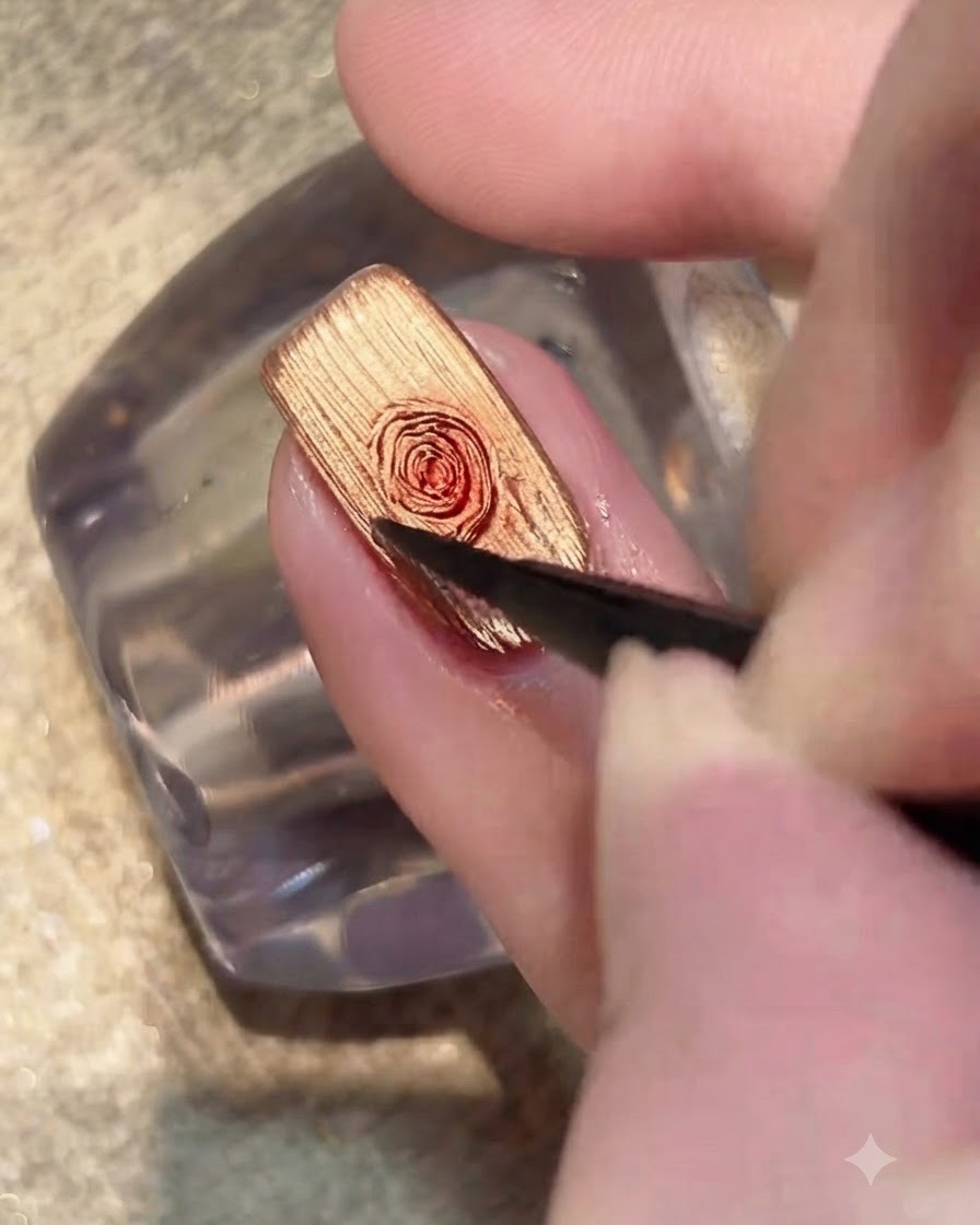 Un pennello che applica uno strato trasparente di blooming gel sulla superficie dellunghia cat-eye dorata.