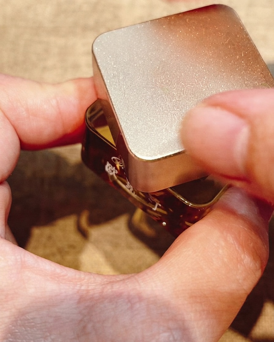 Primo piano di un pennello fine per nail art che disegna cerchi concentrici su un design in gel per unghie.