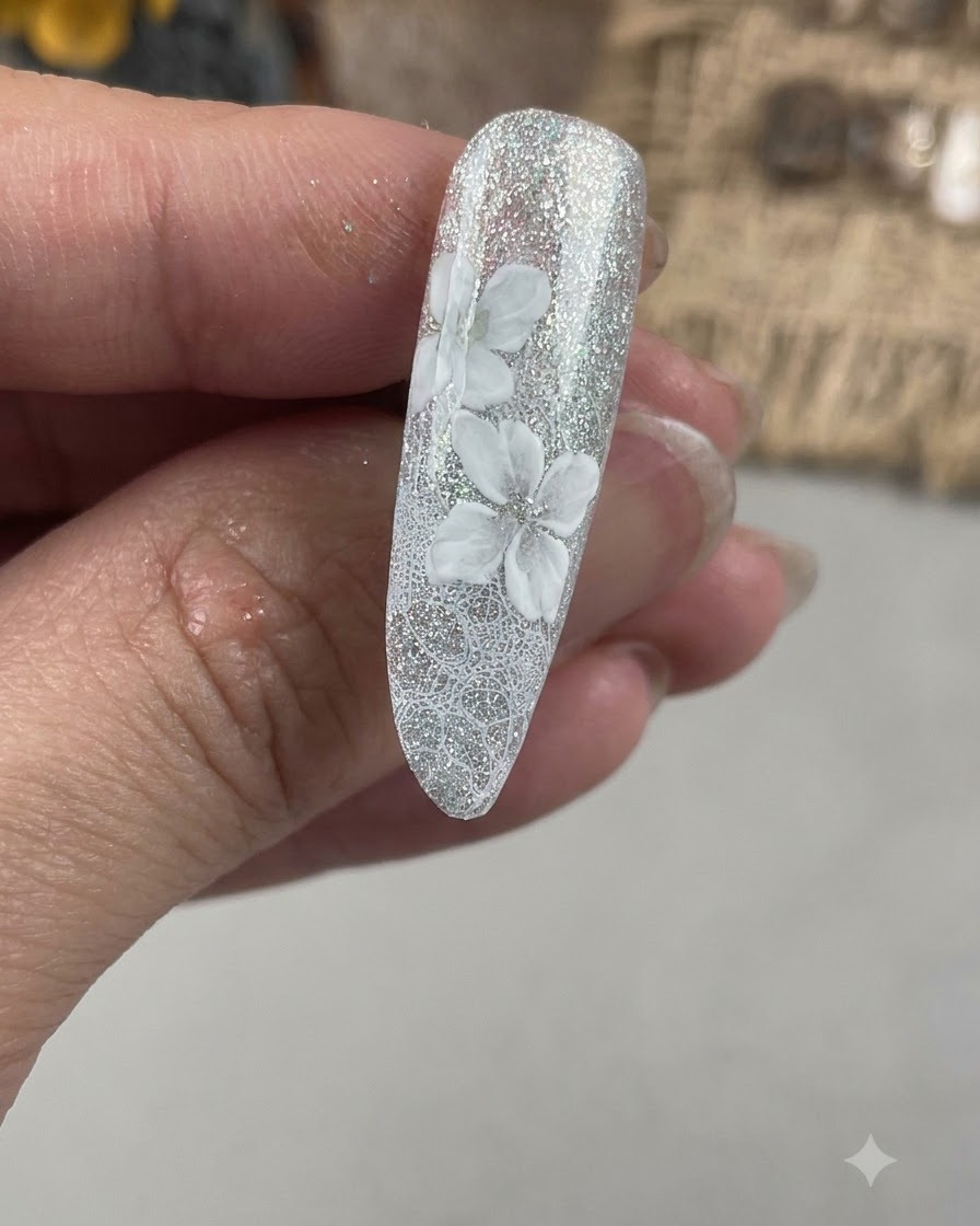 Un primo piano di ununghia che mostra un secondo strato di petali bianchi dipinti in posizione sfalsata rispetto alla base floreale iniziale.