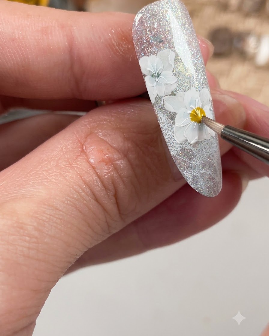 Un pennello per unghie che applica un top coat opaco specificamente sui dettagli floreali bianchi creati sullunghia.
