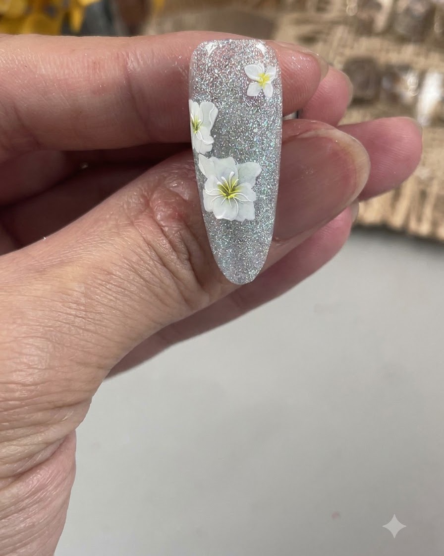 Una vista in primo piano di un pennello fine per nail art che delinea i delicati petali di un fiore bianco su ununghia testurizzata.