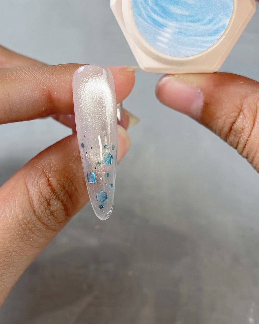 Ununghia a mandorla che mostra una finitura cat-eye lucida con un barattolo di gel di cristallo sullo sfondo.