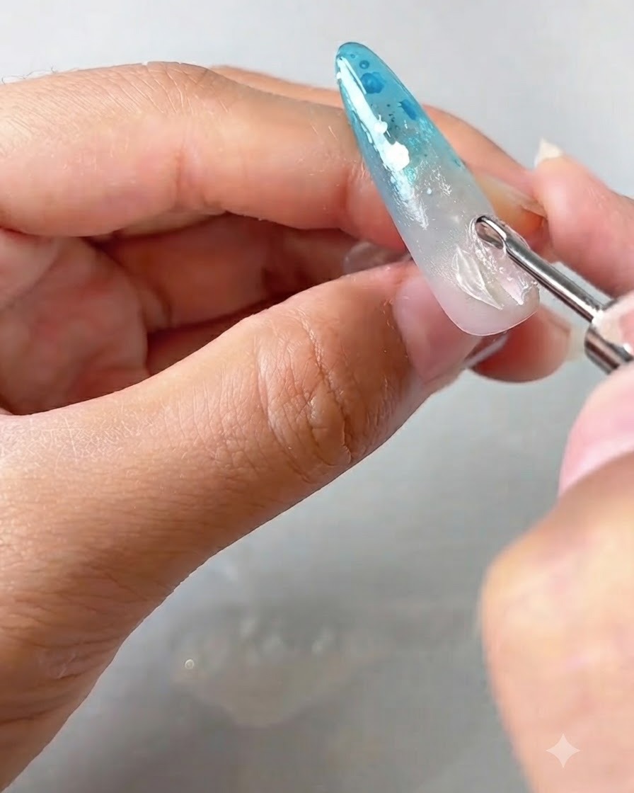 Uno strumento di dettaglio che posiziona e solleva i bordi di un petalo in gel trasparente su ununghia decorata.