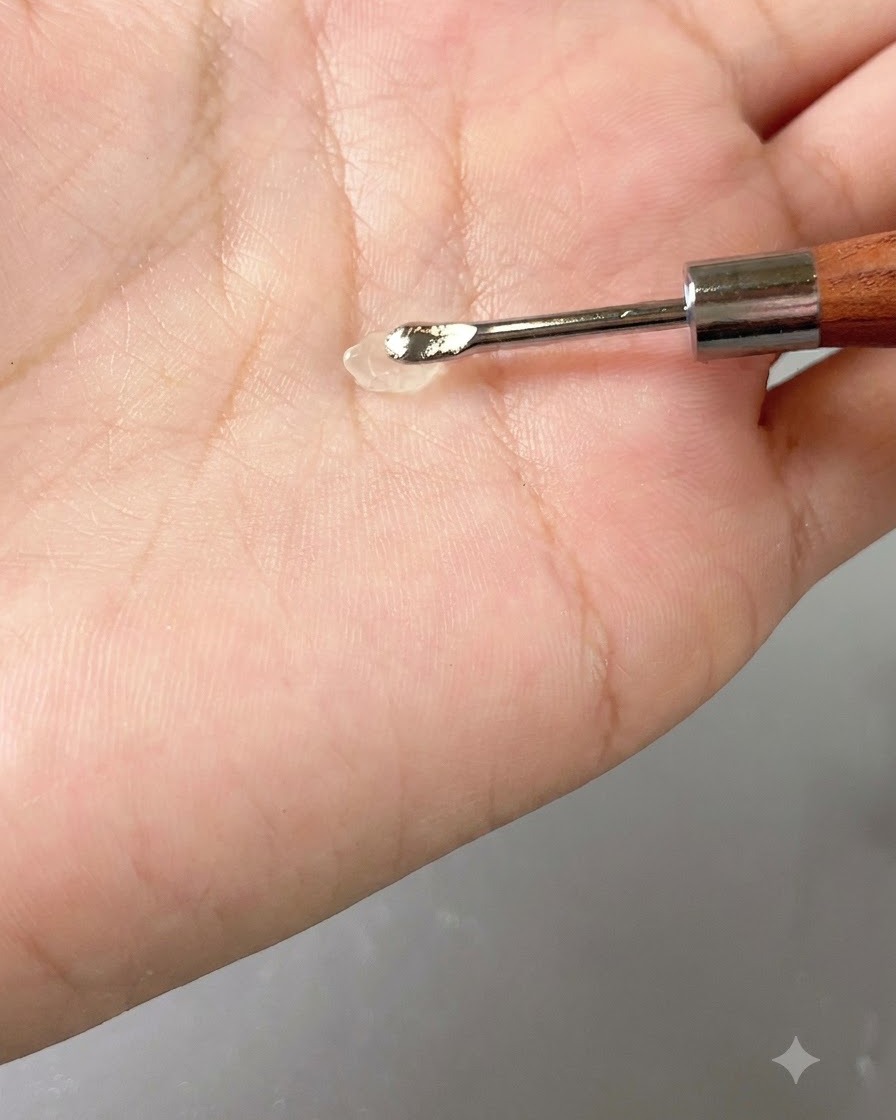 Una piccola goccia di gel trasparente appoggiata su uno strumento manuale contro il palmo.