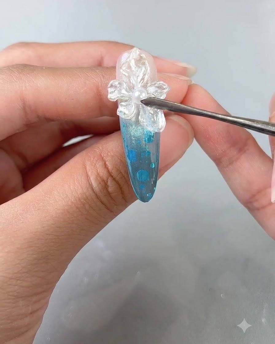 Primo piano di un dito curato che riceve unapplicazione finale di top coat trasparente su un design di nail art con fiori texturizzati.