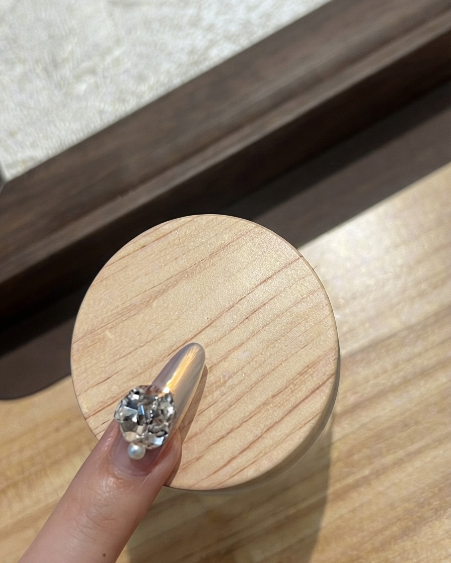 Primo piano di ununghia dellindice decorata con una fila curva di minuscoli strass scintillanti.
