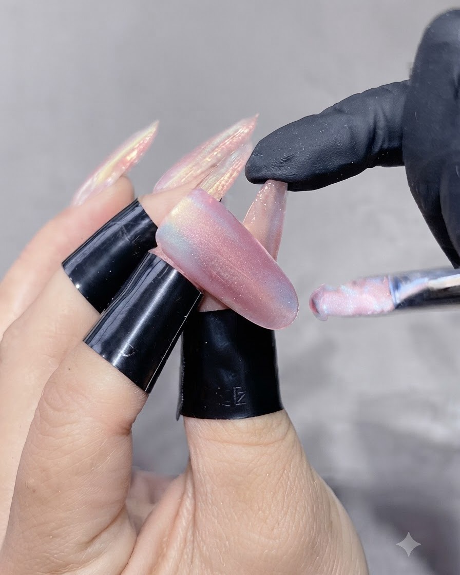 Un pennello per unghie che applica un gel cat-eye brillante su ununghia ricostruita.