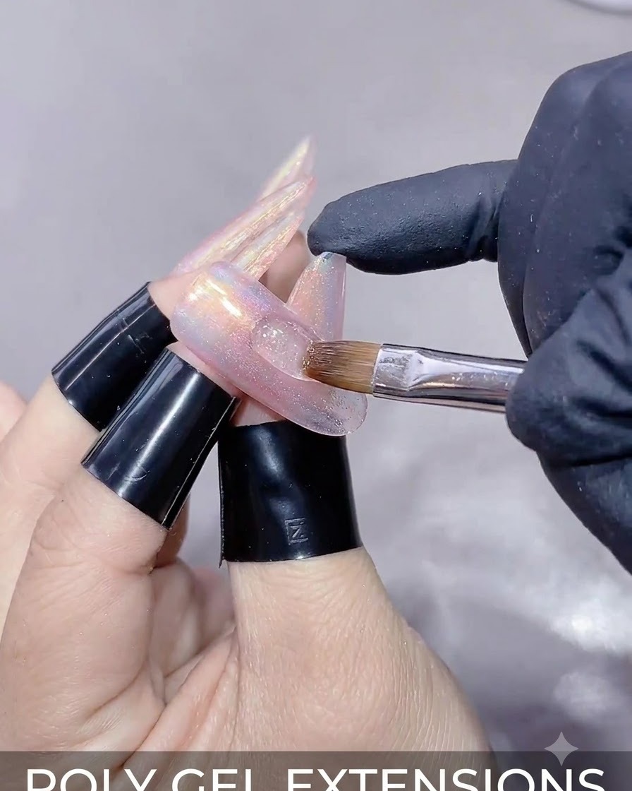 Un primo piano di una mano che tiene una bacchetta magnetica sopra ununghia ricostruita per modellare il riflesso del gel cat-eye.